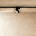 Clérachic black round track light head on a black rail, unlit, showing its flat opal diffuser and slim aluminium drum body.