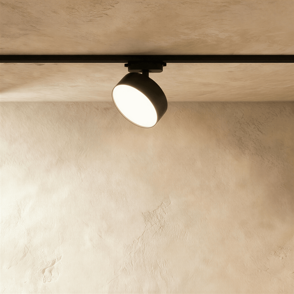 Clérachic larger black round track light head on a black rail, with a wide drum body and a glowing frosted disc face.