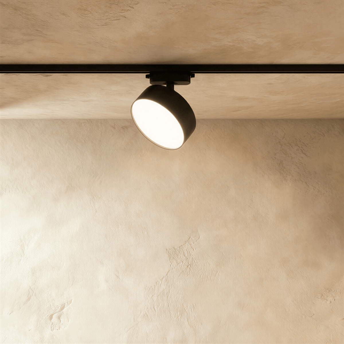 Clérachic larger black round track light head on a black rail, with a wide drum body and a glowing frosted disc face.