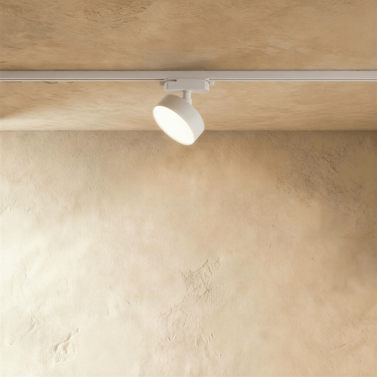Clérachic white round track light head on a white rail against a warm plaster ceiling, its slim disc face softly lit.