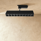 Clérachic long black ten-spot track spotlight bar with deep recessed lenses, unlit, on a track adaptor and chrome stem.