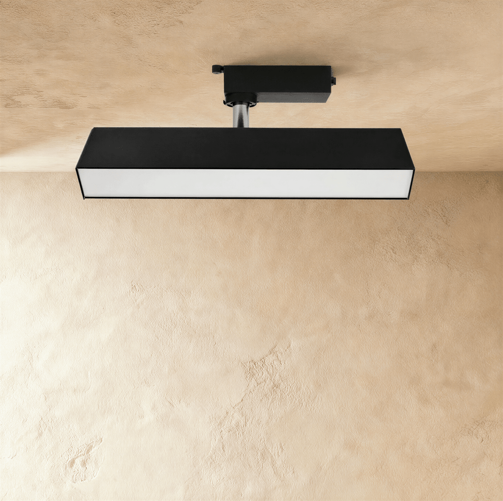 Clérachic medium black rectangular linear track light with a long frosted diffuser, hung from a track adaptor on a chrome stem.