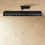 Clérachic extra-long black track spotlight bar with fifteen deep recessed lenses, on a track adaptor and chrome stem.