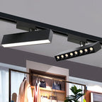 Clérachic black linear track light and an eight-spot track spotlight bar on a black rail above a clothing rail in a shop.
