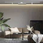 Clérachic white track system with a spotlight bar and two cylinder spots above a stone-toned sofa and large leafy plant.