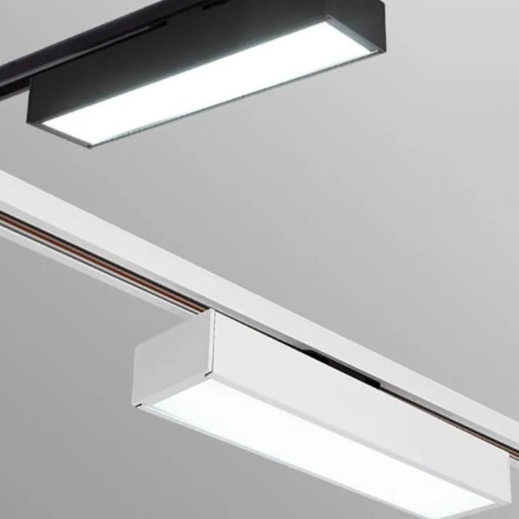 Close view of a Clérachic black linear track light above a white linear track light, both with bright frosted diffusers on rails.