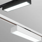 Close view of a Clérachic black linear track light above a white linear track light, both with bright frosted diffusers on rails.