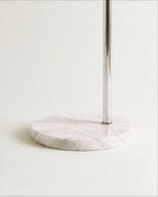 A close view of the Clérachic floor lamp's round white marble base, where the polished chrome pole meets the stone.