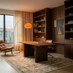 Beside a walnut desk and bookshelves, the orange dome of this Clérachic floor lamp casts a warm pool of light.
