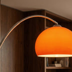 A close-up of the glossy orange dome shade on this Clérachic floor lamp, glowing warmly against a wood-panelled room.