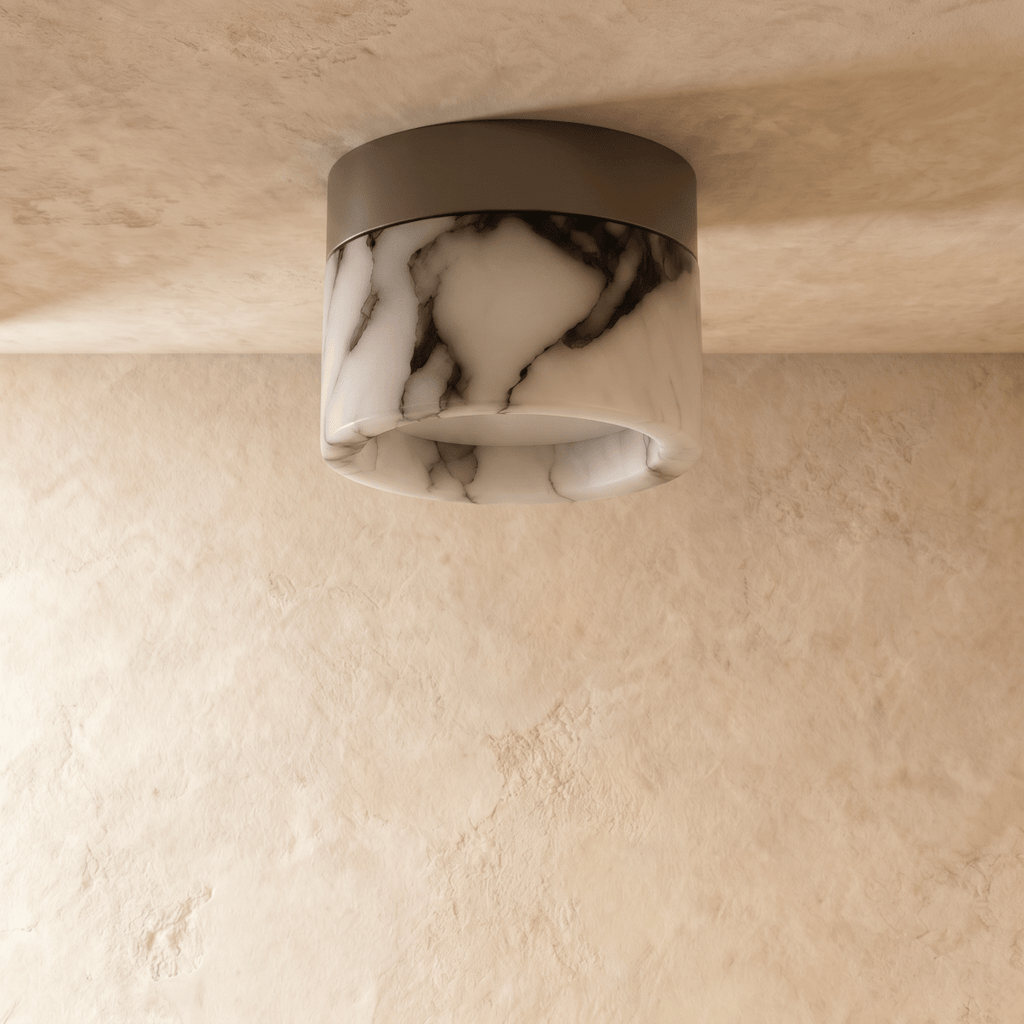 Clérachic unlit marble drum ceiling light with dark natural veining on a black metal mount, against a plaster ceiling.