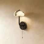 Clérachic marble dome wall light on a limewash plaster wall, the veined stone shade lit with the brass pull chain hanging beneath