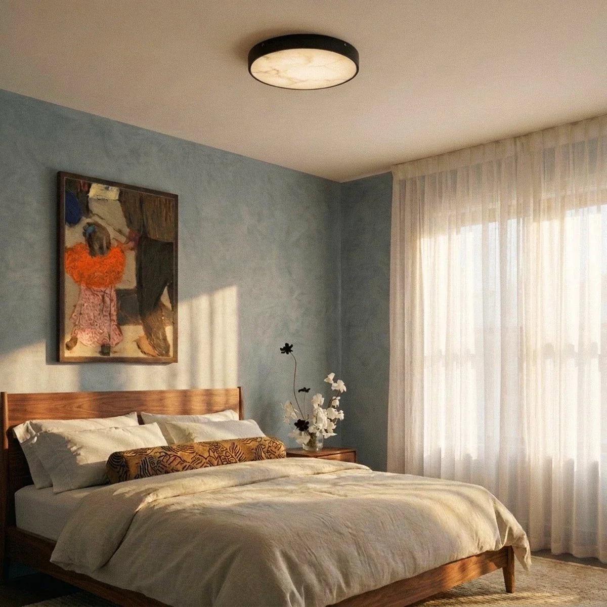 Clérachic round marble-diffuser ceiling light above a walnut bed in a bedroom with a blue wall and sheer curtains.