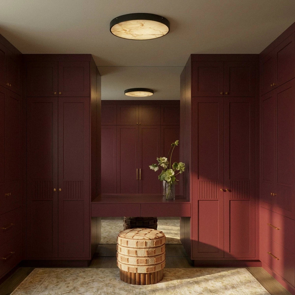 Clérachic marble-diffuser ceiling lights lit in a burgundy dressing room, one overhead and one reflected in the mirror.