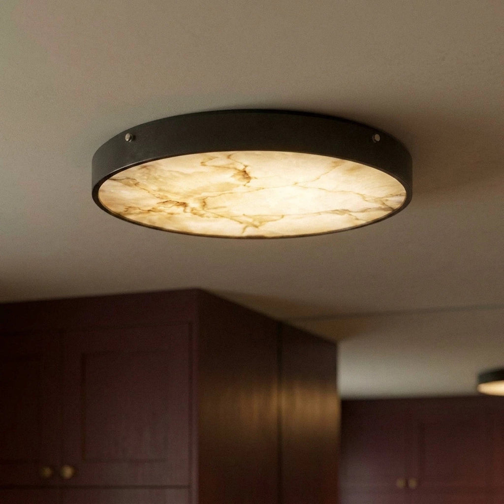 Clérachic flush ceiling light seen from below, its lit marble diffuser and dark rim with two visible fixing screws.