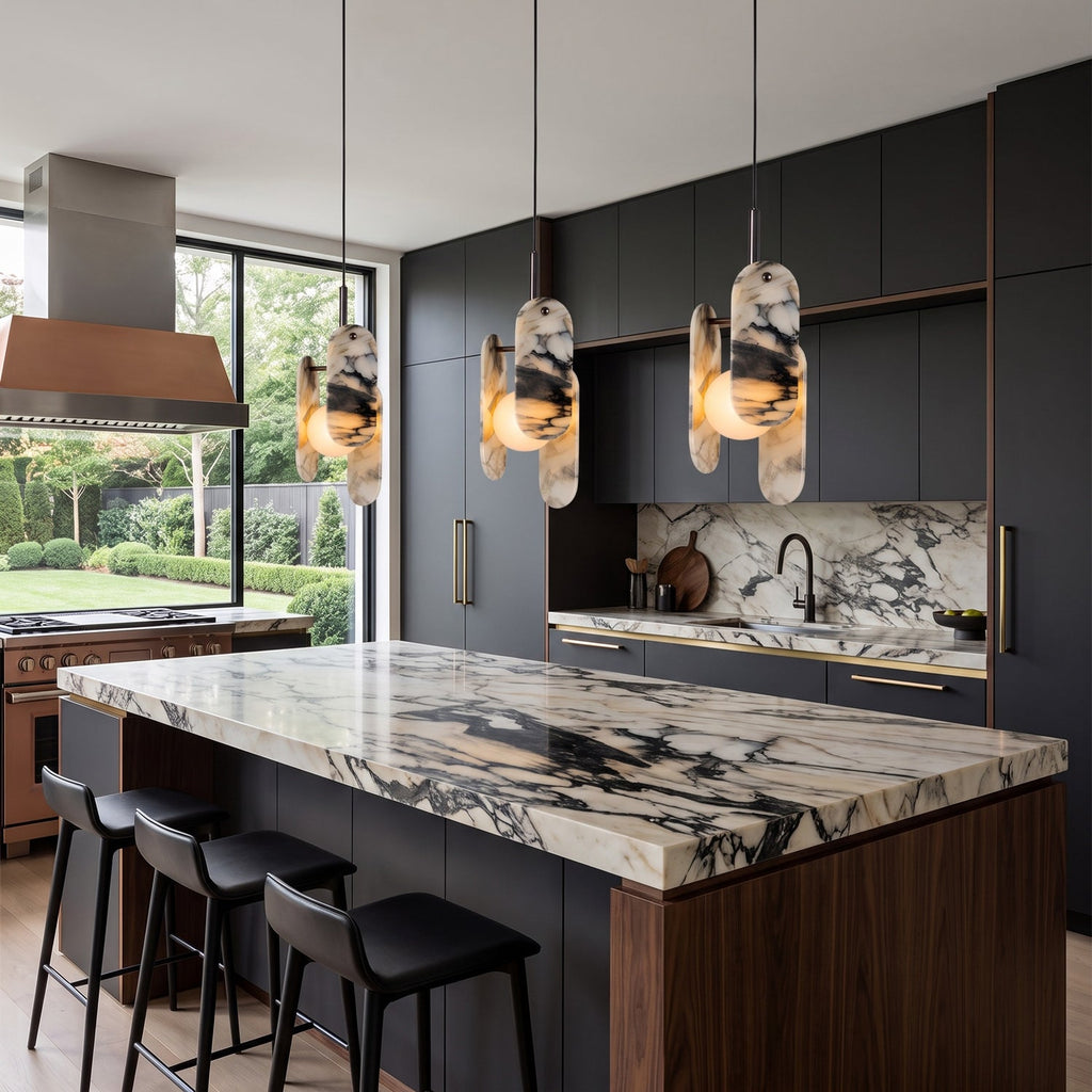 Three Clérachic marble pendants hang over a marble-topped island with a walnut base and black bar stools, in a dark kitchen.