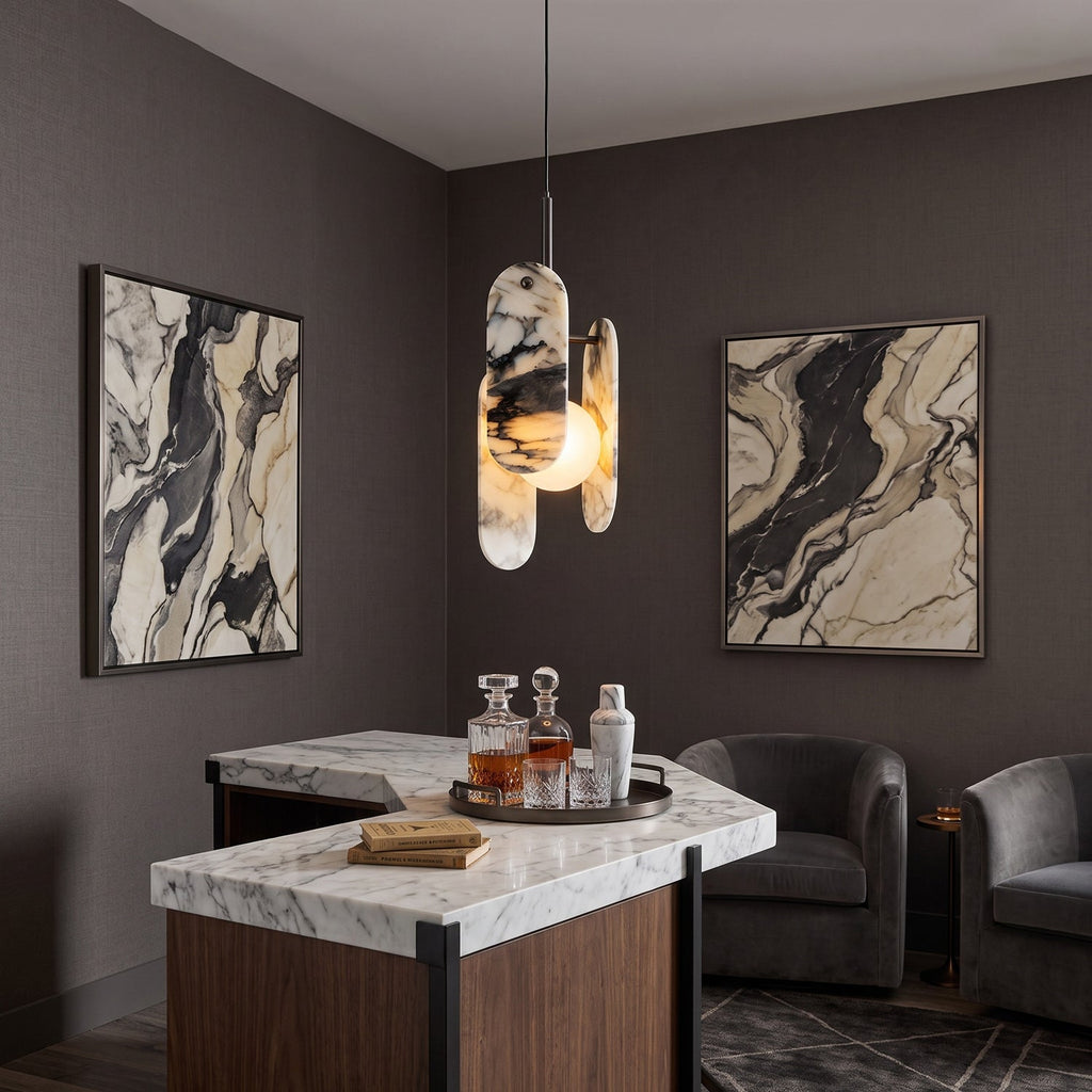 A Clérachic marble pendant hangs over a marble-topped bar with a drinks tray, between two framed marbled artworks.