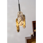 The cream and amber-veined marble panels on this Clérachic pendant glow warm from the globe inside, above a rattan-fronted cabinet.