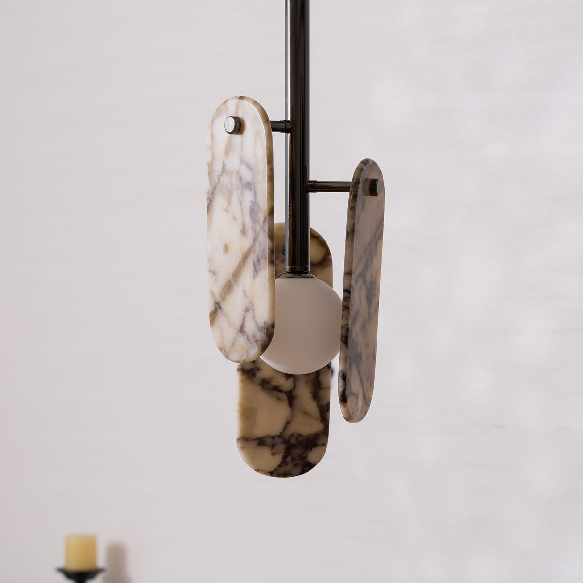 Close view of the metal arms that hold the cream marble panels and the frosted globe on this Clérachic pendant.