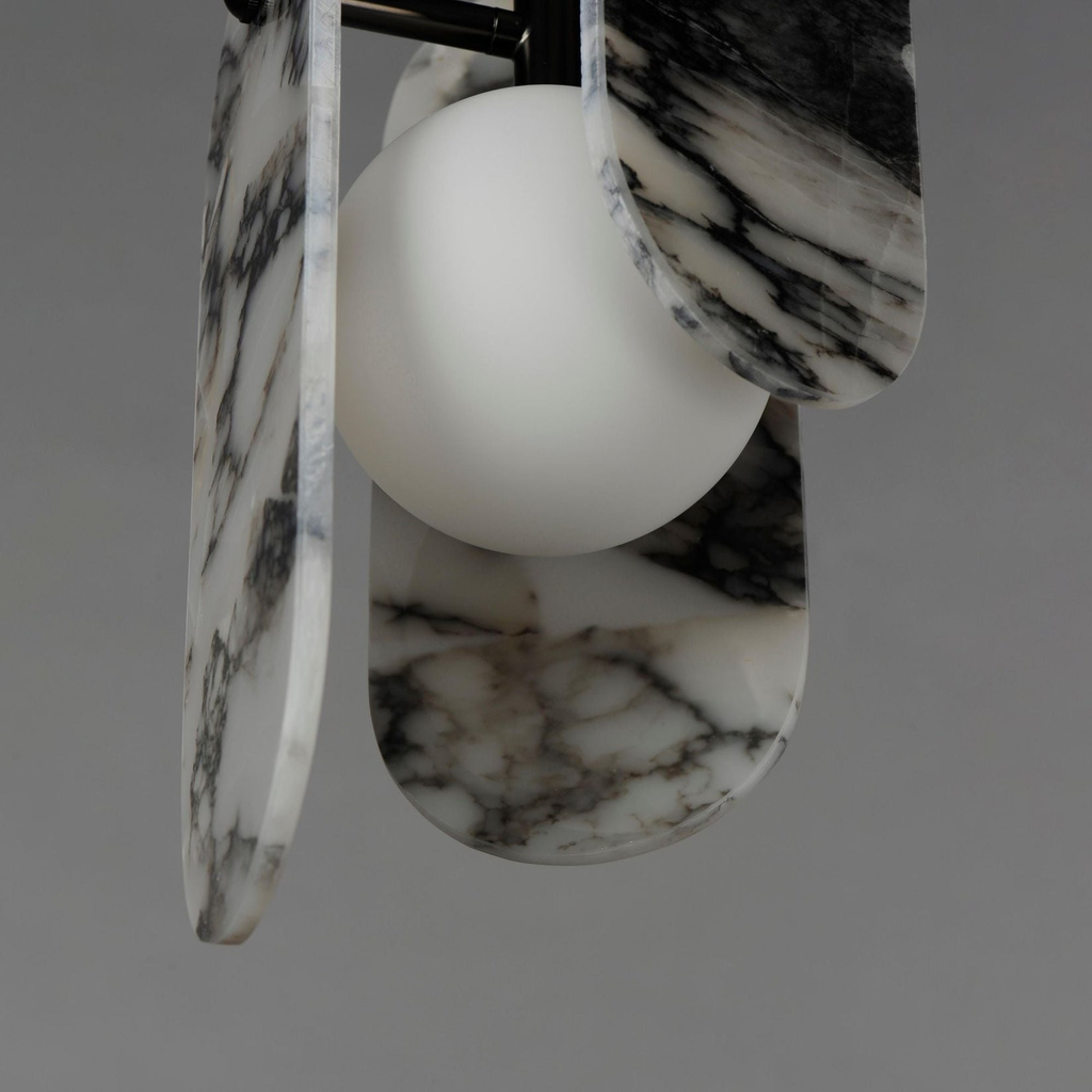 Close view of black-veined white marble panels and a frosted glass globe on this Clérachic pendant, on a grey backdrop.