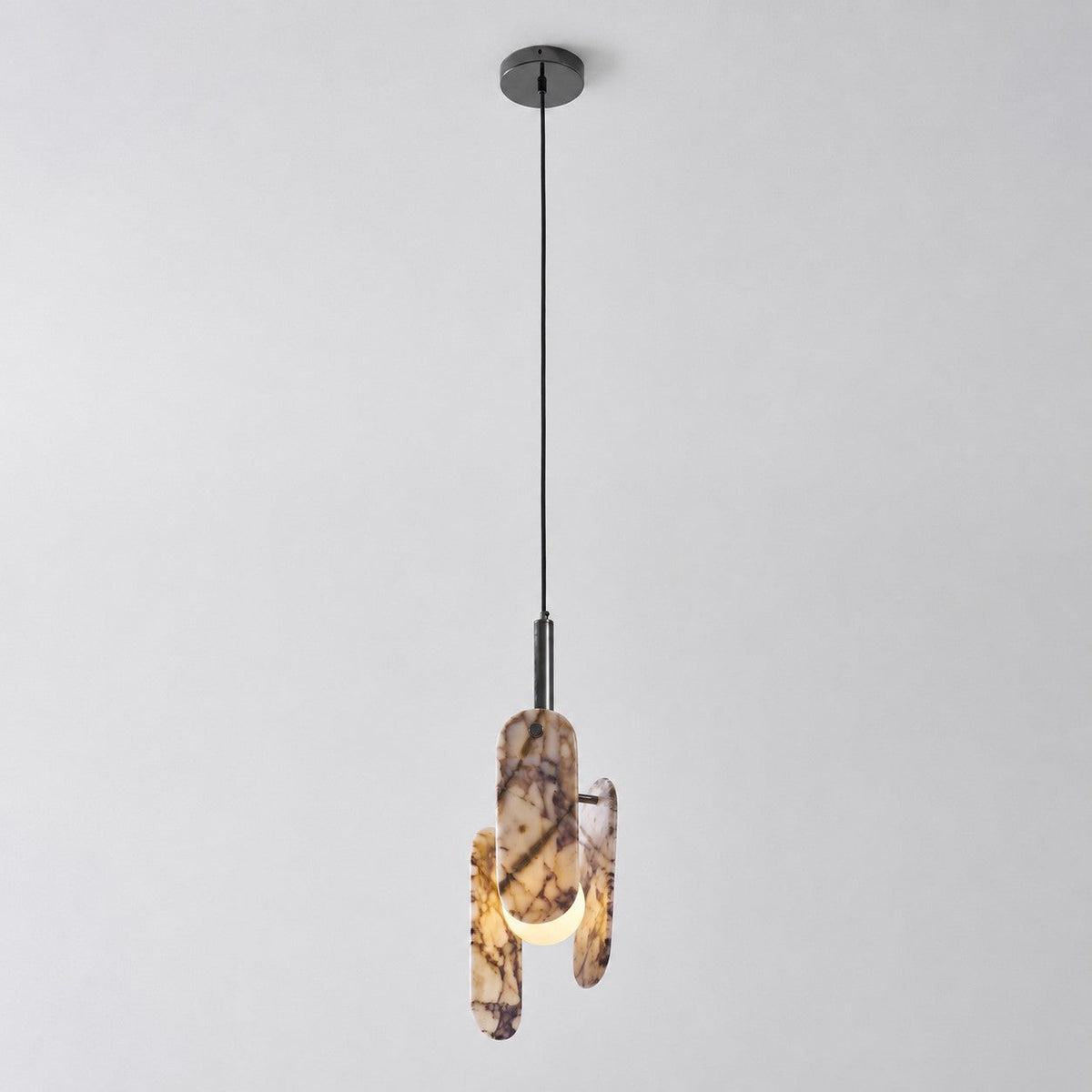 The Clérachic pendant in a cream marble version with violet veining, hung from a black cord and canopy on a pale backdrop.