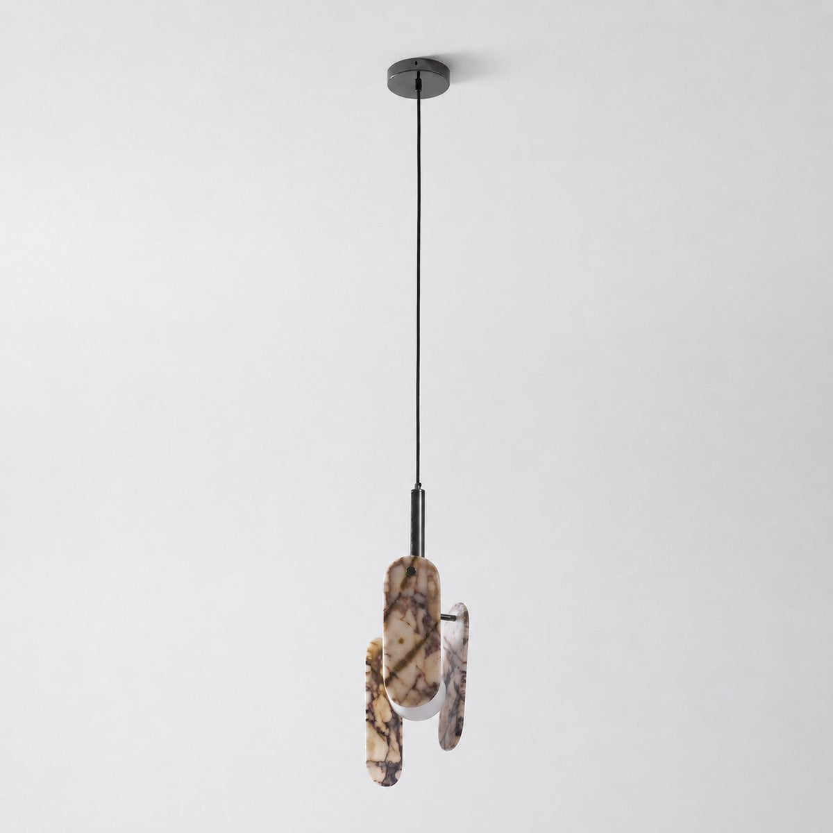 A cream marble version of this Clérachic pendant on a black cord and round black canopy, with its globe softly lit.