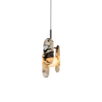 A Clérachic marble pendant in black and white, lit warm behind its oval panels, on a black cord against a plain white backdrop.