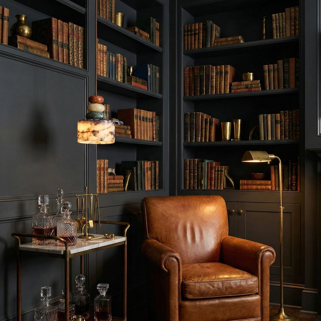 Lit Clérachic pendant in a dark panelled library, hanging near full bookshelves, a leather armchair and a drinks trolley.