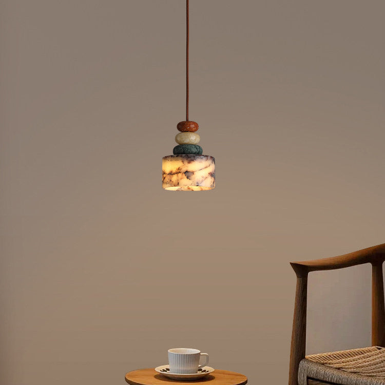 Clérachic pendant lit against a warm taupe wall, with a small wooden side table and cup of coffee low in the frame.