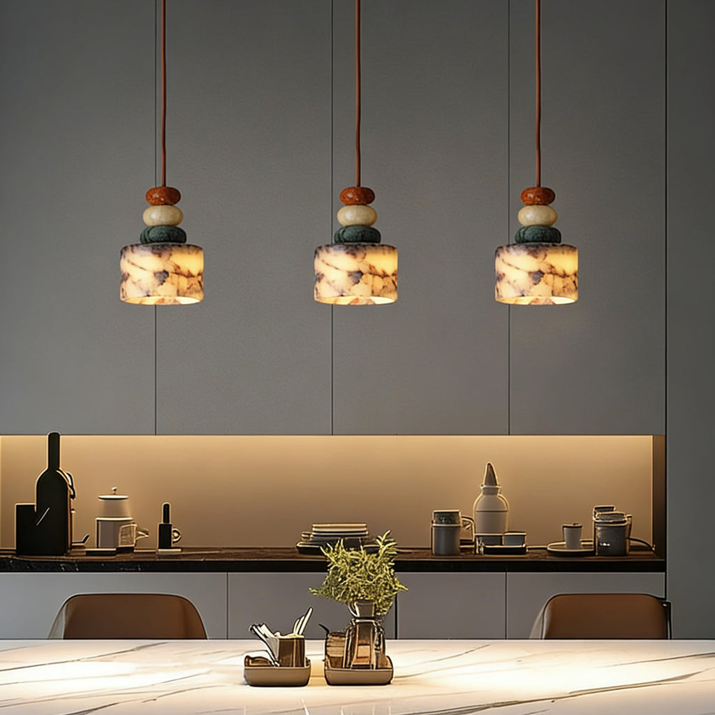 Three Clérachic pendants lit in a line above a kitchen counter with a glowing shelf, pale worktop and a small plant in a pot.