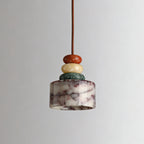Unlit Clérachic pendant against a soft grey backdrop, showing the white marble drum with plum-coloured veining under three stone beads.