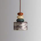 Straight-on view of this Clérachic pendant switched off, a marble drum with fine dark veining below its stacked stone beads.