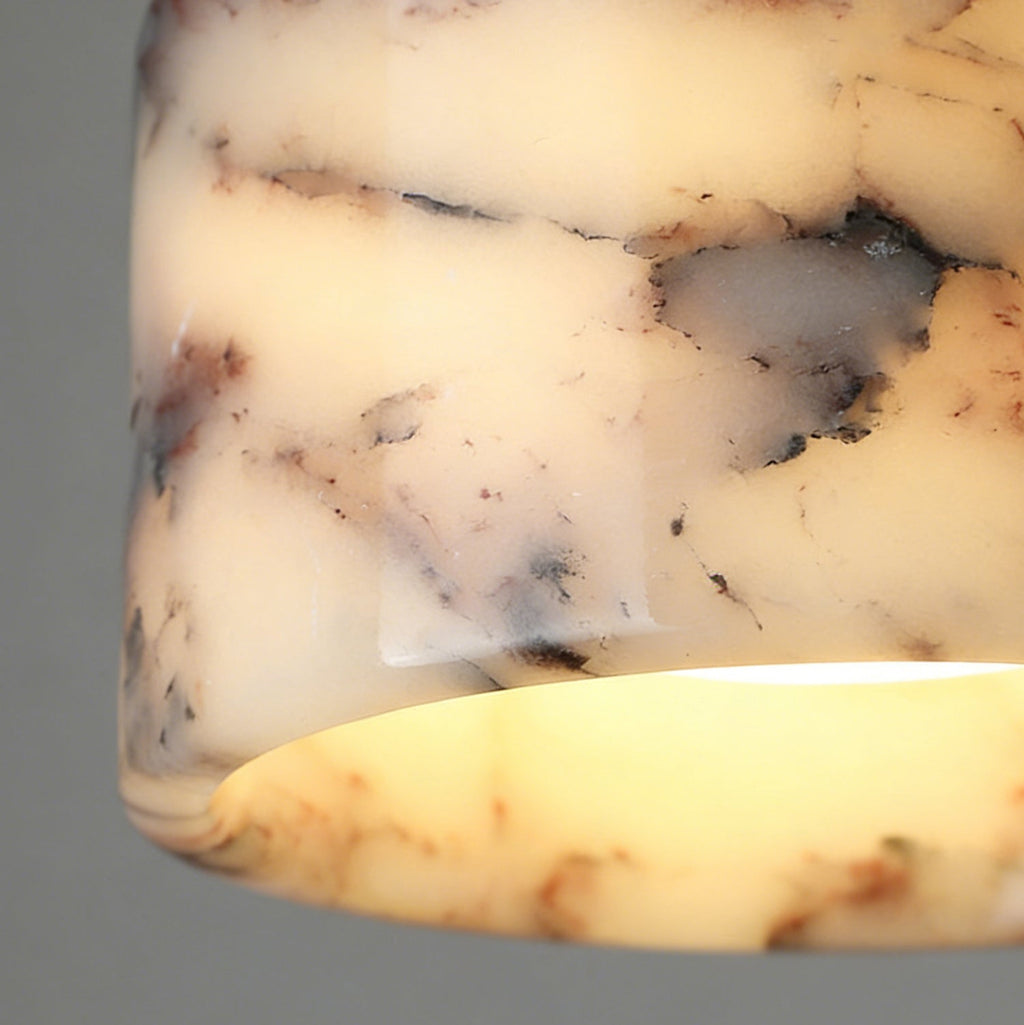 Close view of the lit marble shade on this Clérachic pendant, with its glowing rim and cream, grey and rust veining.