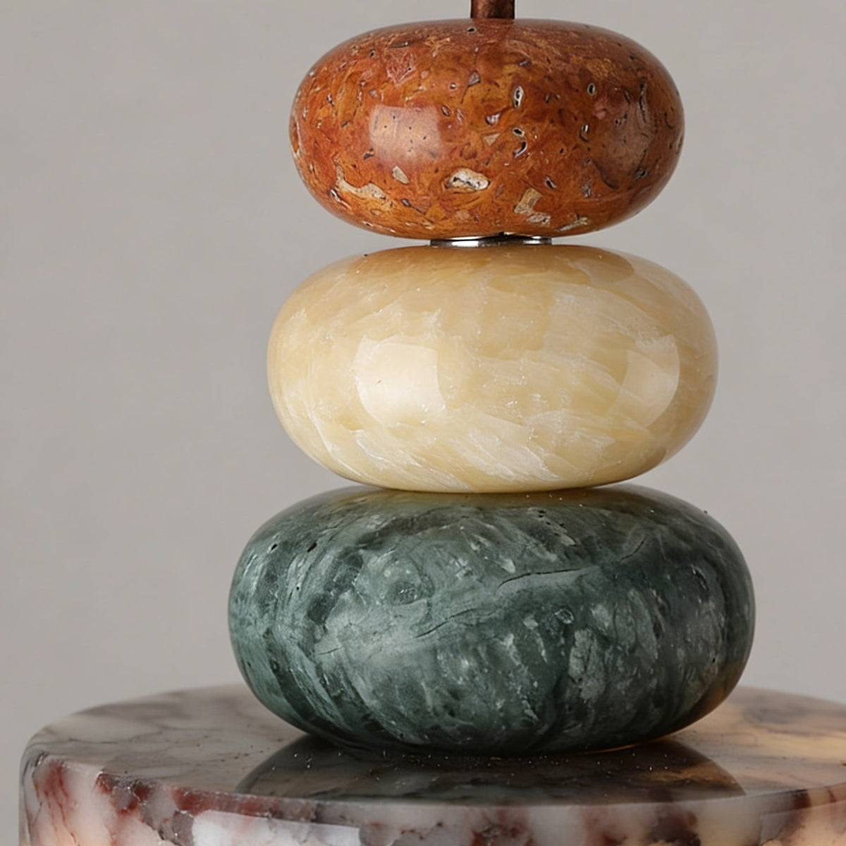 Close view of the rust, cream and green stone beads stacked above the marble drum of this Clérachic pendant.