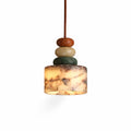 Cut-out view of this lit Clérachic pendant on white, its marble drum glowing warm below the rust, cream and green beads.