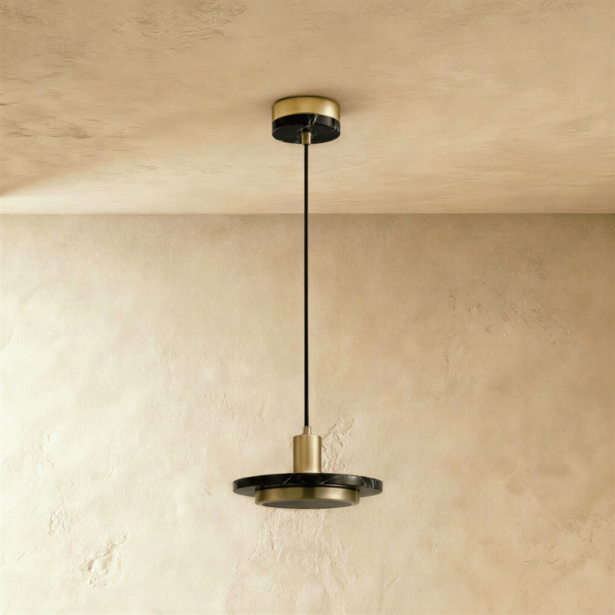 Clérachic brass-finish pendant with a black marble plate and a switched-off round diffuser, on a limewash wall.