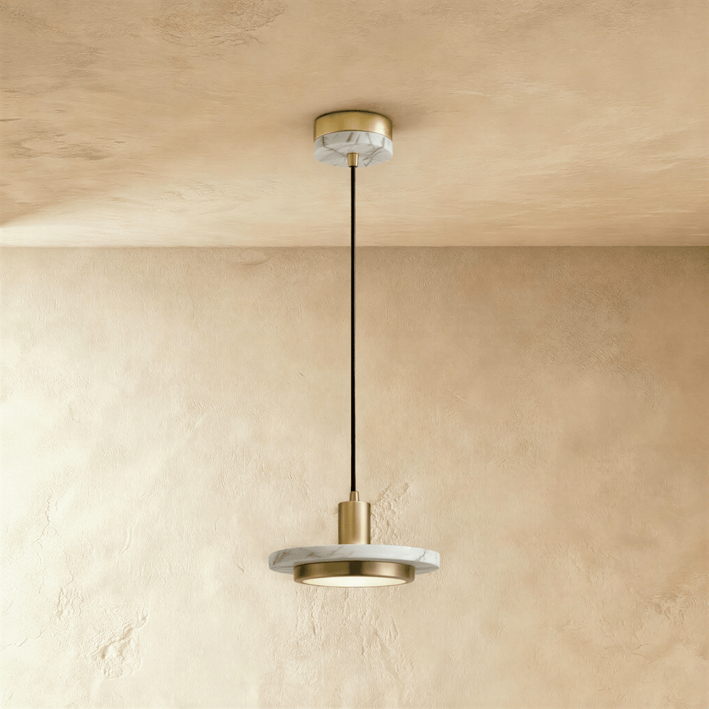 Clérachic brass-finish pendant light with a white veined marble plate and round diffuser on a limewash wall.