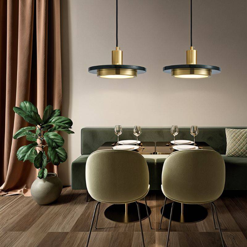 Clérachic pair of dark green marble and brass pendant lights above a set dining table with olive green chairs.