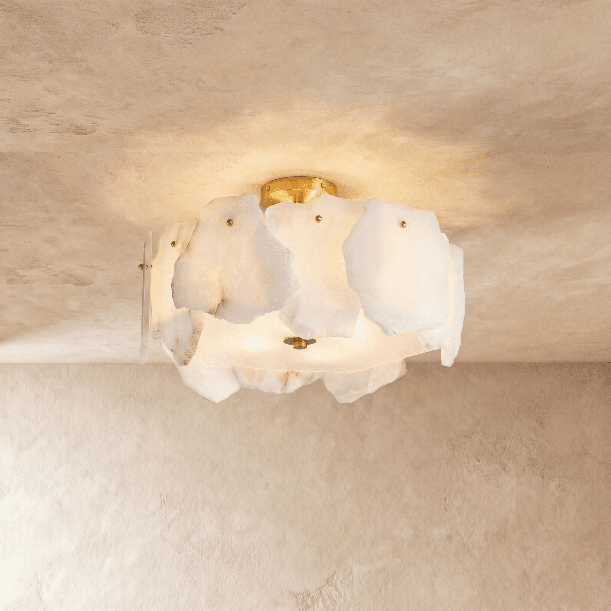 Clérachic semi-flush ceiling light with veined white stone slabs glowing warmly, brass canopy above, on a plaster ceiling.