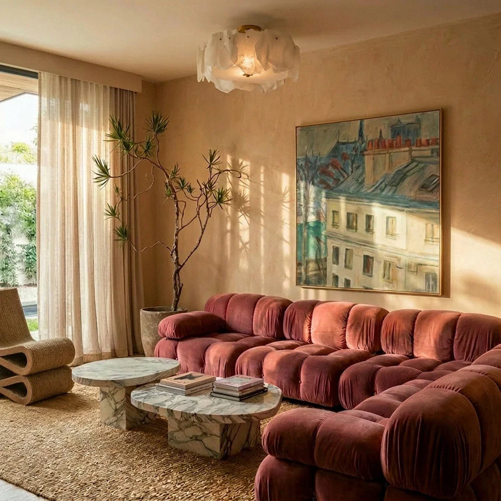 Clérachic stone-slab ceiling light above a living room with a rose velvet modular sofa, marble coffee tables and a landscape painting.