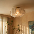 Clérachic stone-slab ceiling light glowing in a warm peach living room, with sheer curtains and a tall potted plant below.
