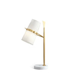 A Clérachic table lamp with a gold stem and white marble base, the white shade tilted to the left, shown on a plain white background.