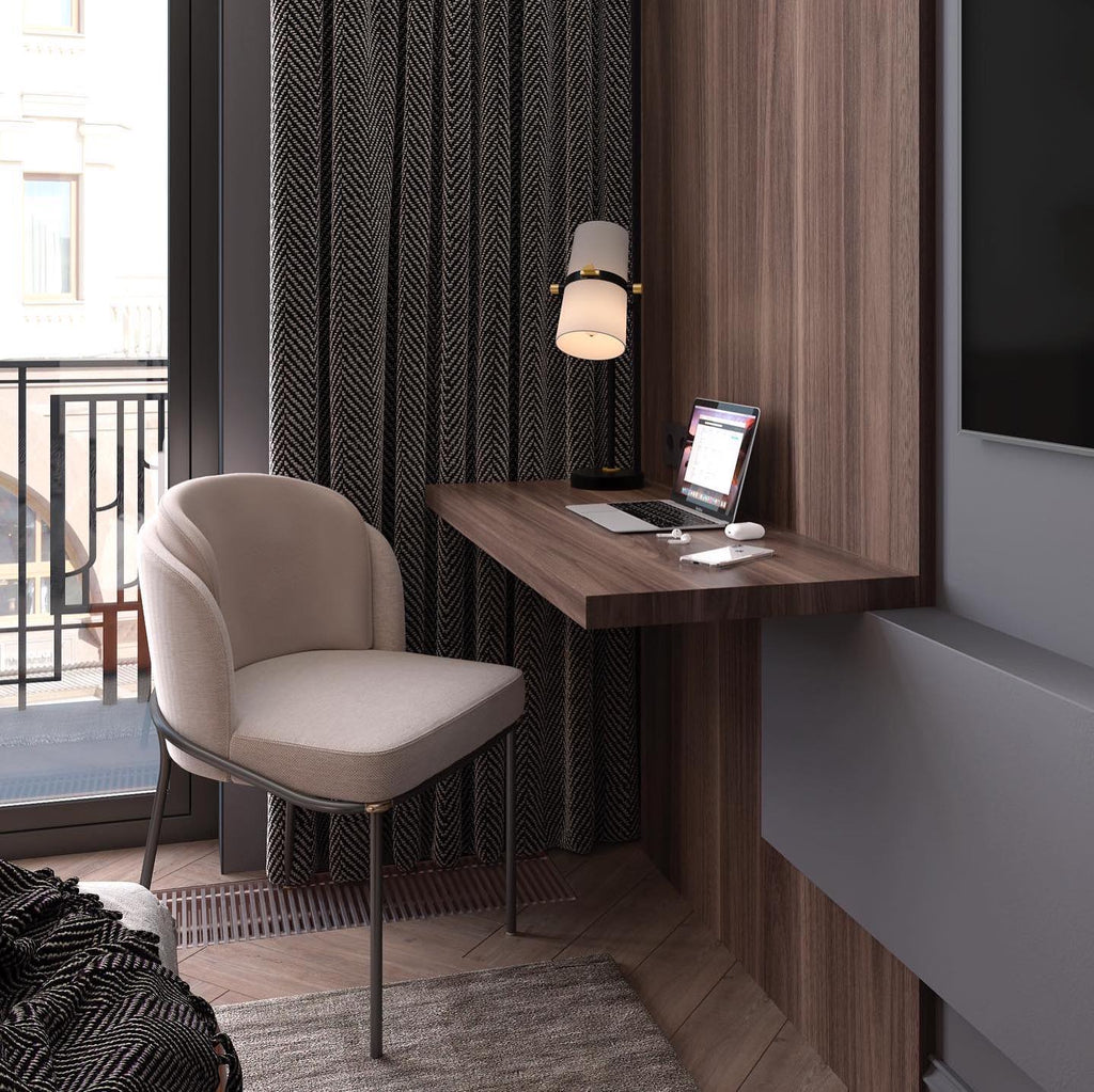 Slim wall-hung desk with a laptop and a lit Clérachic table lamp, beside a taupe chair and dark ribbed curtains.