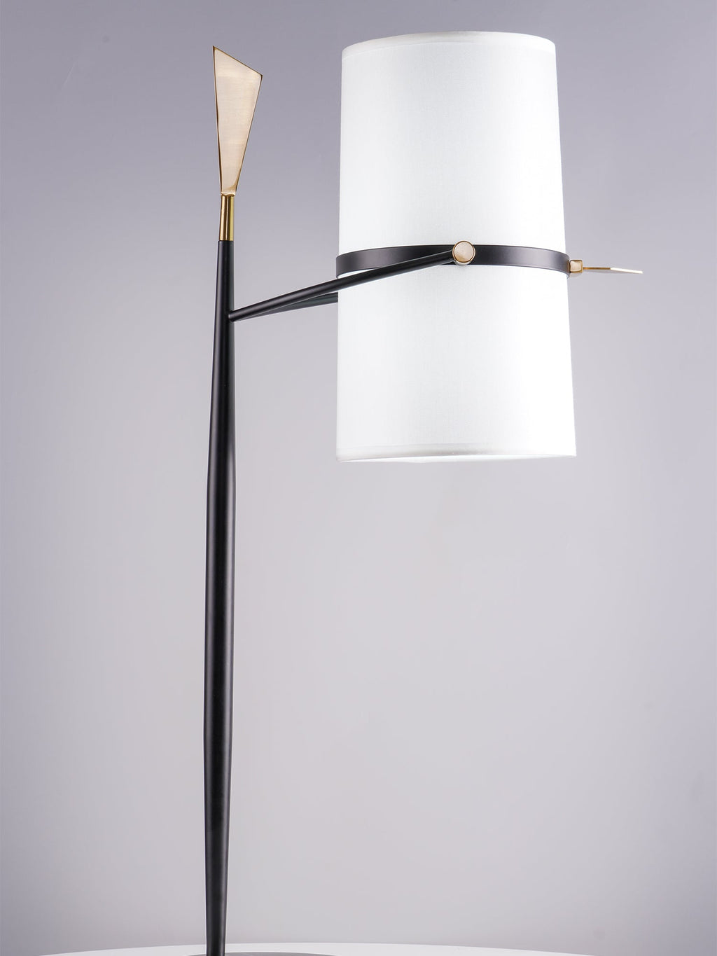 Clérachic table lamp with the shade held upright on a black stem with a gold tip, against a soft lilac-grey backdrop.