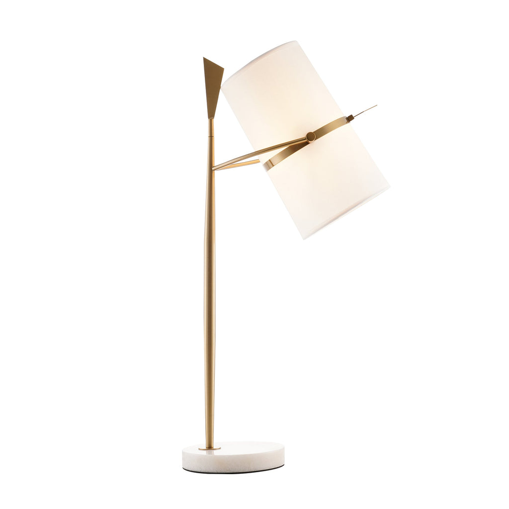 Gold-stemmed Clérachic table lamp on a white marble base, its shade tipped and softly glowing, on a white background.