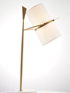 Gold-stemmed Clérachic lamp glowing against a bright white studio backdrop, its cream shade tilted down to the right.