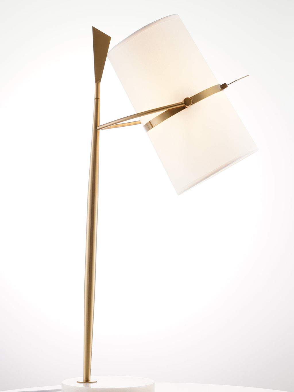 Angled close view of this gold Clérachic table lamp, its cream shade tilted against a bright, hazy studio backdrop.