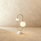 Clérachic table lamp with two opal glass globes on a brass arc over a rounded marble base, unlit.