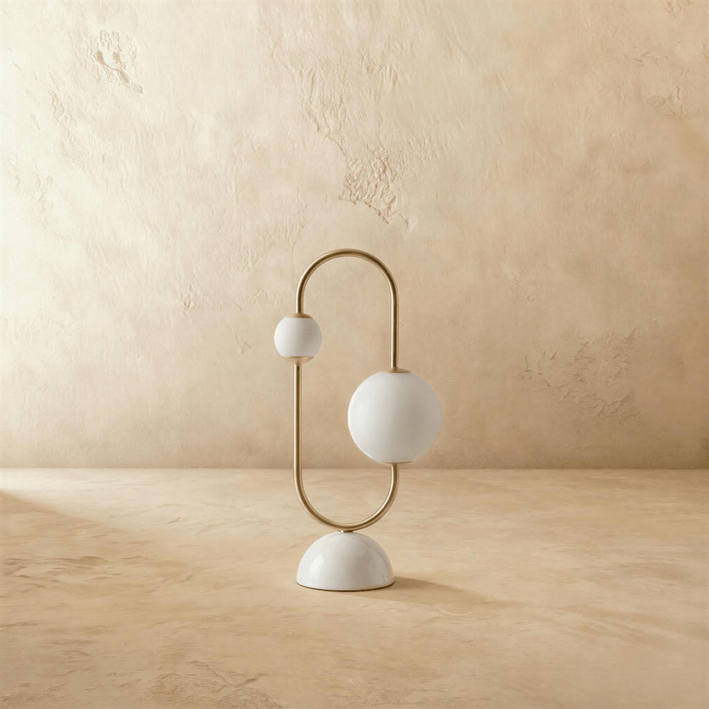 Clérachic table lamp with two opal glass globes glowing on a brass arc over a rounded marble base.