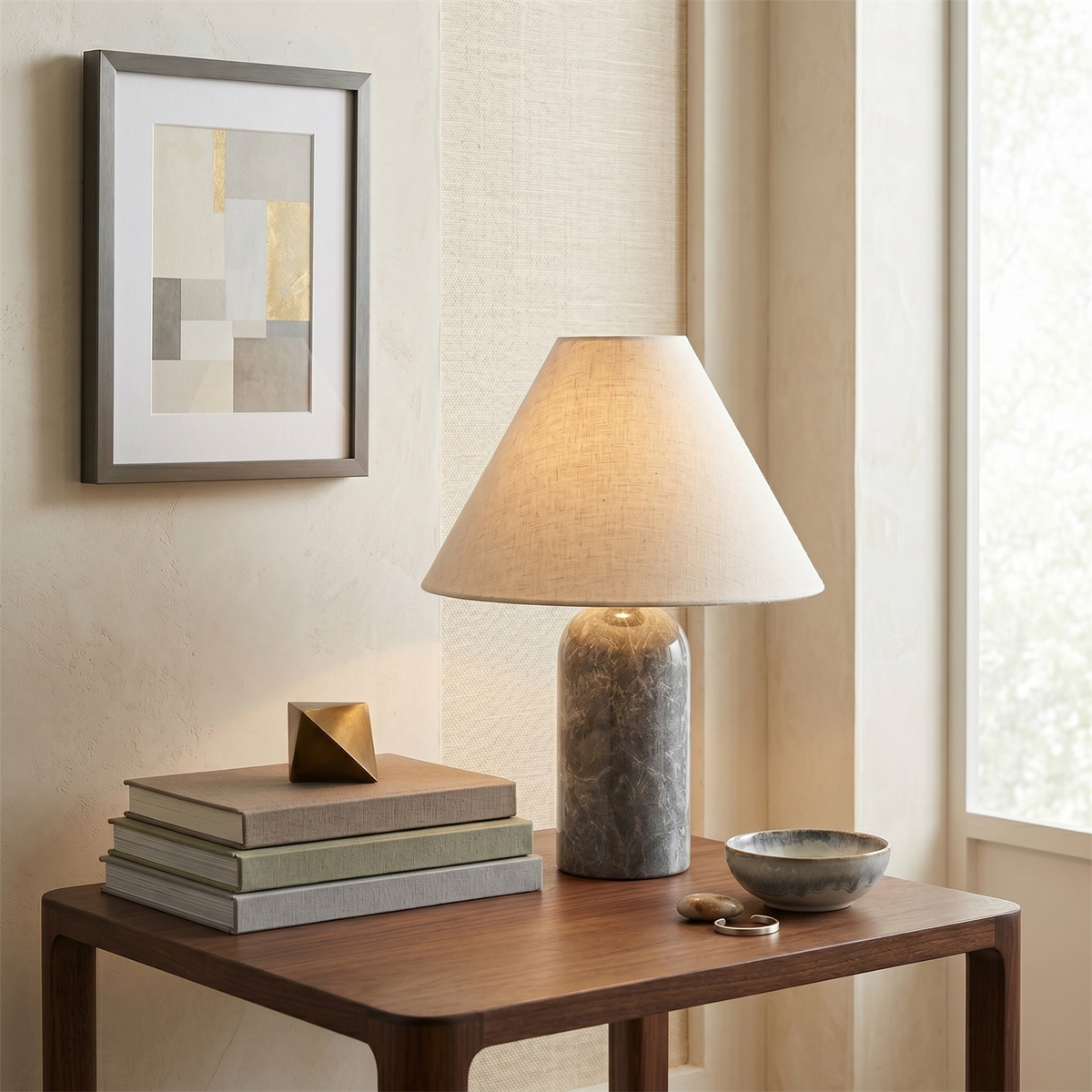 Grey marble base and a softly glowing linen shade on this Clérachic table lamp, set on a wooden side table by a bright window.